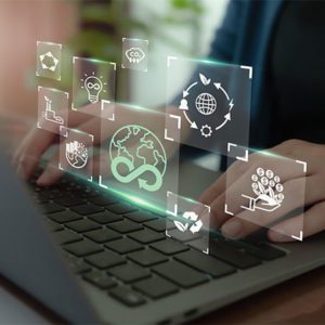 Hands typing on a laptop with translucent sustainability and ESG icons floating above the keyboard, including recycling, globe, CO₂, renewable energy, ethics, and circular economy symbols, representing sustainable business and digital responsibility. Credit: Shutterstock