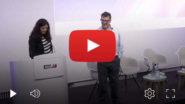Speaker Prof Saeema Ahmed-Kristensen standing at a DIGIT Lab podium while Prof Roger Maull stands beside a panel discussion stage with chairs and a small table, shown in a video player interface.